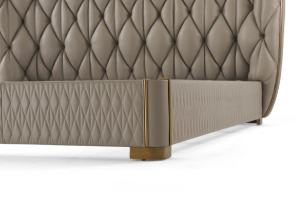 Quilted taupe leather king bed close up of brass adorned leg.