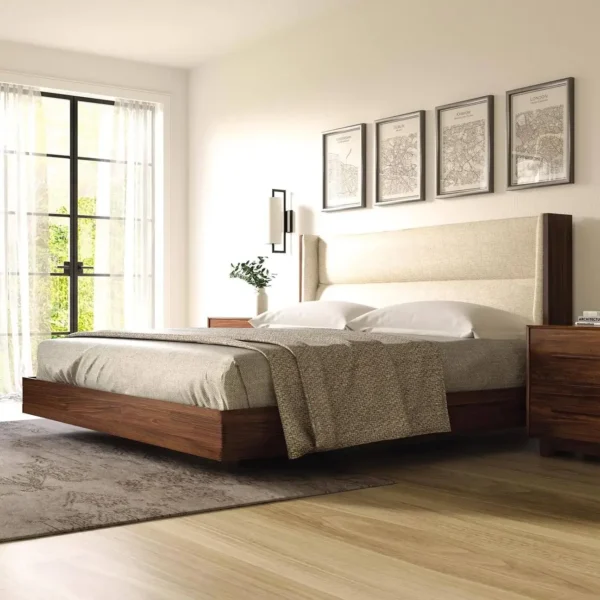 Modern floating walnut platform bed with upholstered headboard in a cream fabric in an empty sunlit room.