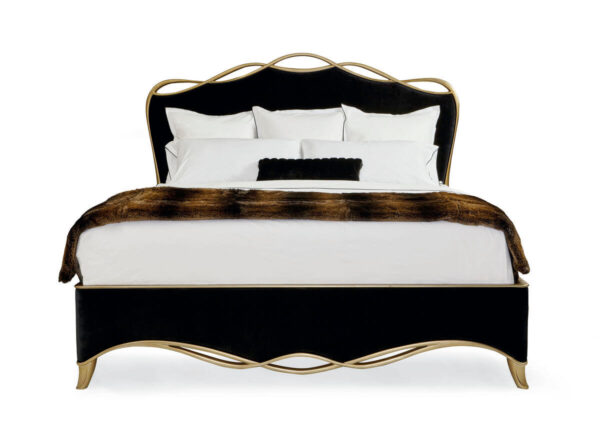 The black ribbon bed by Caracole in a black velvet fabric with a gold finish wood trim in a ribbon like form.
